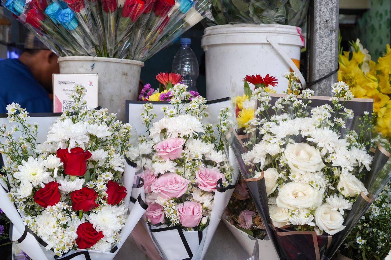 Vibrant rose and chrysanthemum bouquets on display at a flower stall in Indonesia.