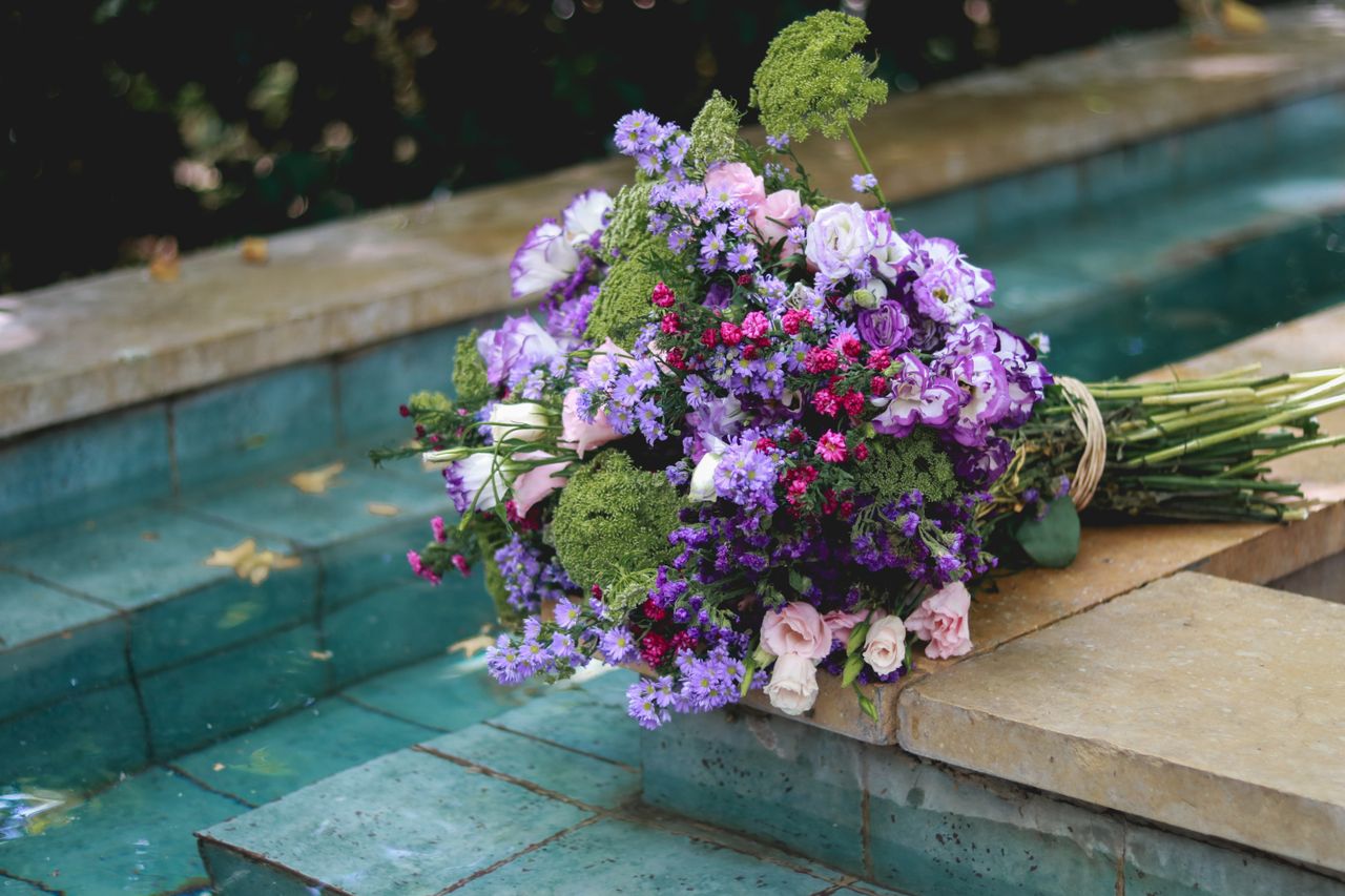 A colorful bouquet of flowers resting beside a calm pool, creating a serene and elegant scene.
